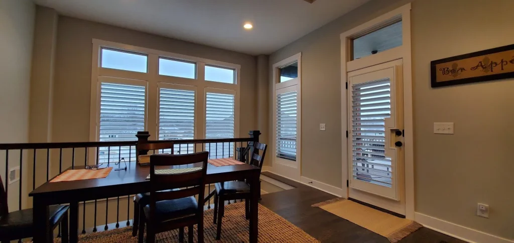 Dining area with large windows and shutters.