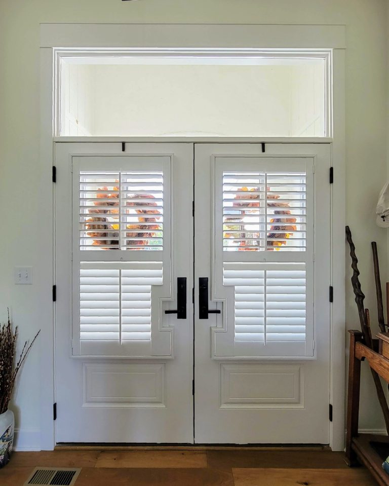White double doors with fall wreaths and shutters.