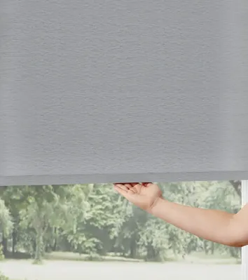 Hand adjusting gray window roller shade.