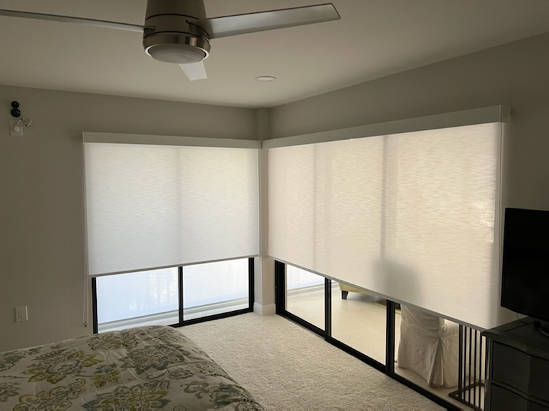 Bedroom with closed roller blinds and ceiling fan.